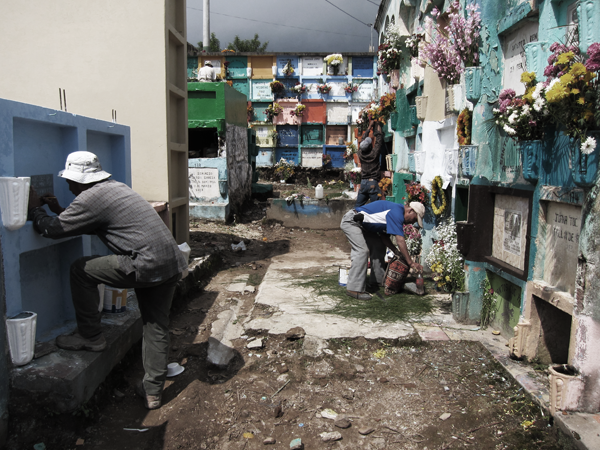 Local men painting and decorating family tombs on Dia de Los Muertos in Solola, Guatemala